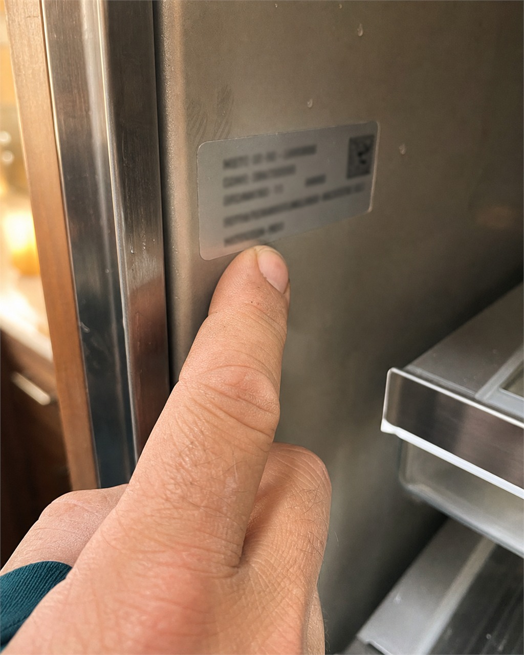 Local Campbell technician checking the model and serial tag inside a Sub-Zero built-in refrigerator